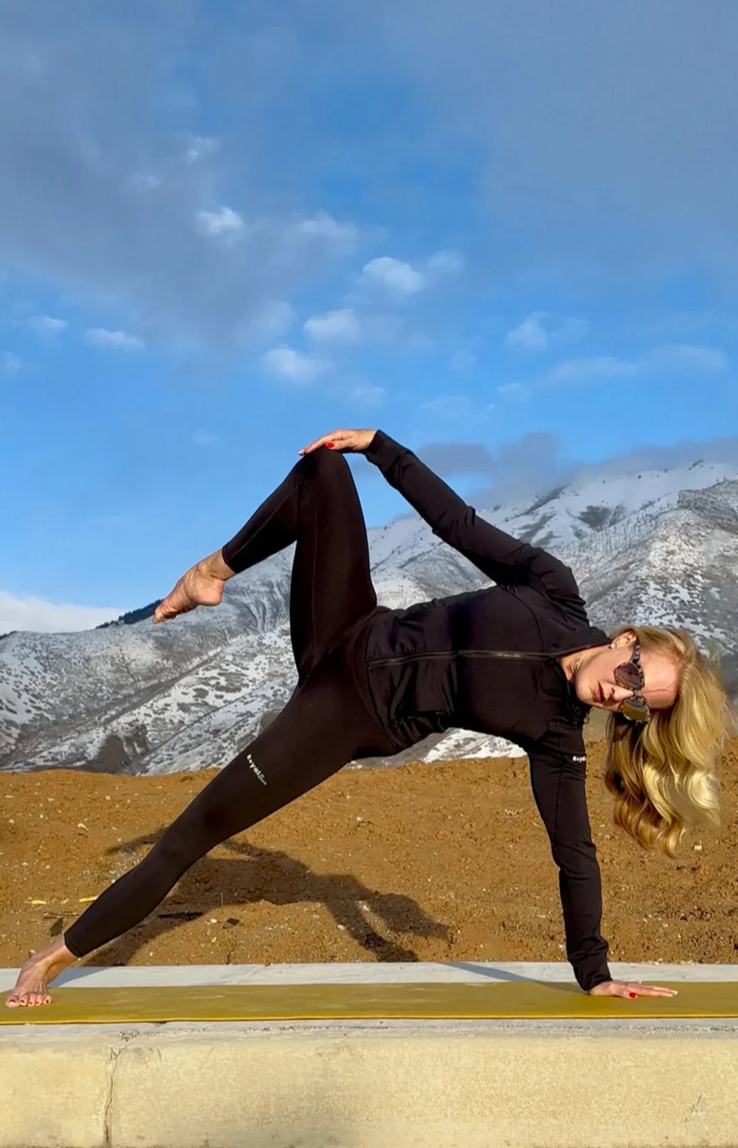 Person practicing yoga on a mat with mountains in the background